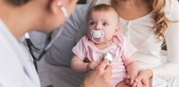 istockphoto-664046882-612×612 Beautiful young mom is holding her cute baby while doctor is listening to baby's lungs